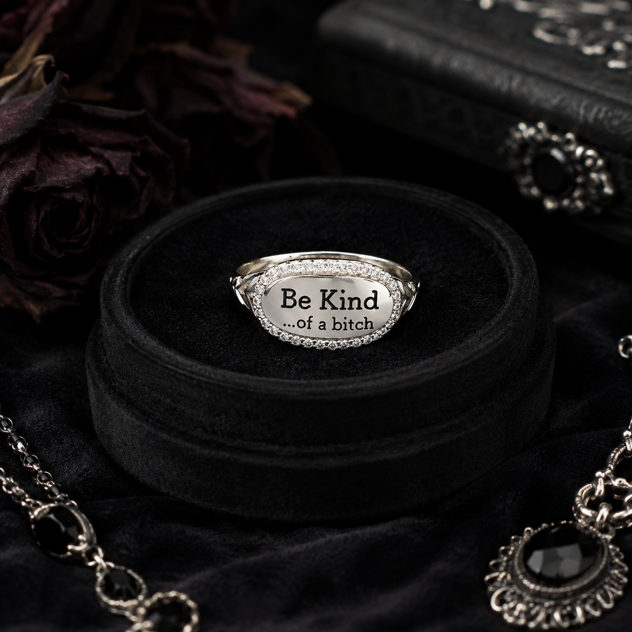 A silver oval ring with the engraved text 'Be Kind .