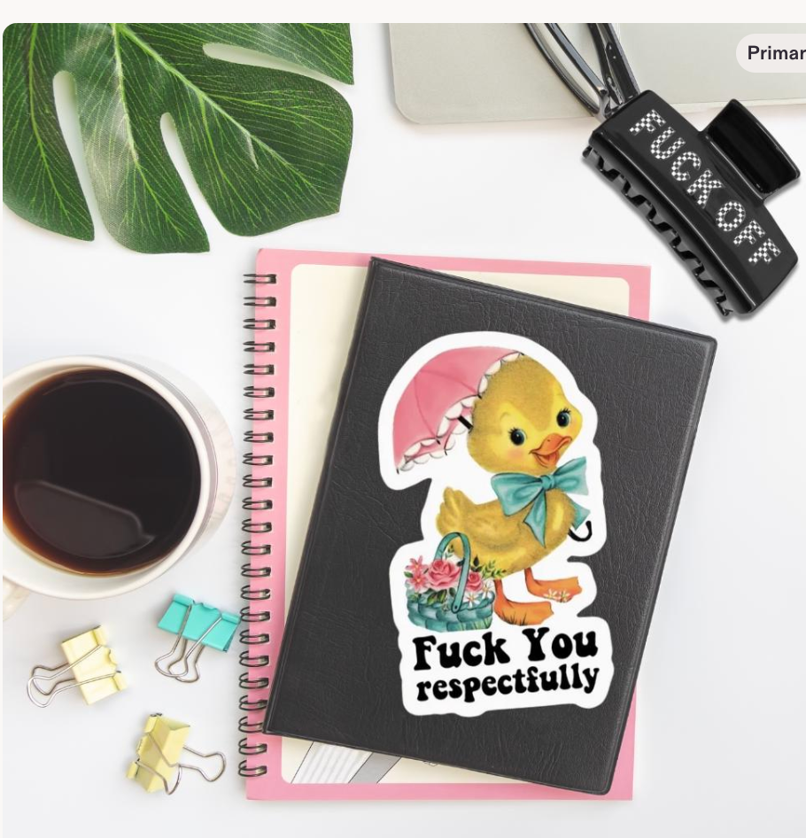 A black spiral notebook with a die-cut sticker of a yellow duckling holding a pink umbrella and bow tie, with the text 'Fuck You respectfully' printed below it. The notebook is styled in a flat-lay arrangement with a coffee cup, binder clips, a plant leaf, and a hair clip on a white background.