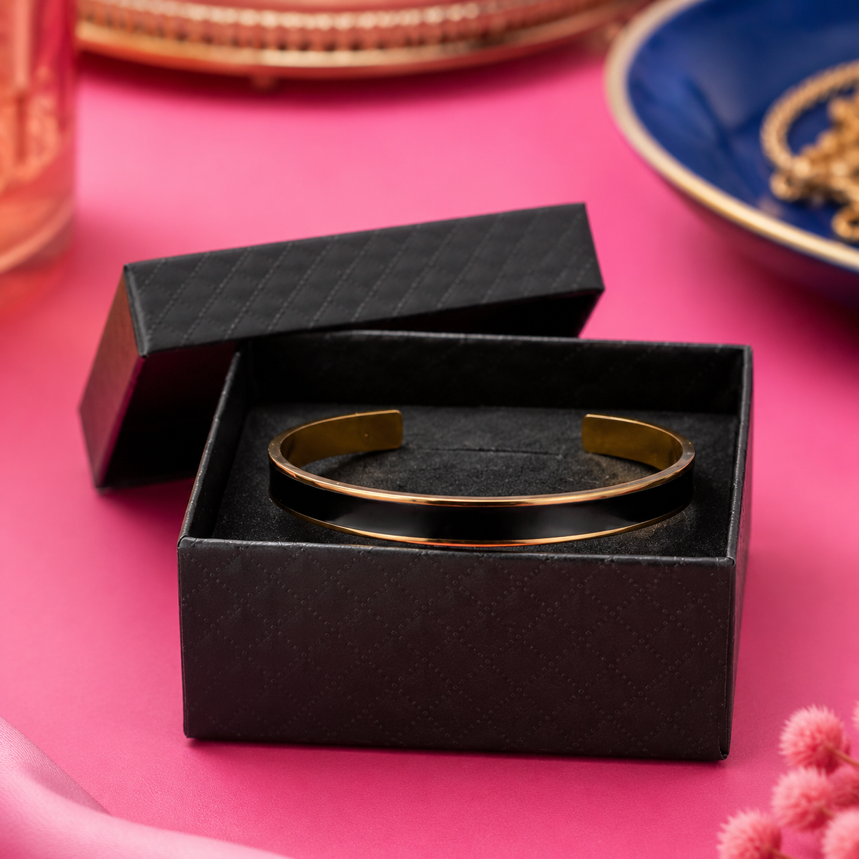 Black and gold cuff bracelet showing its polished black exterior inside an open black gift box