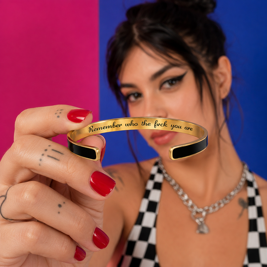 Model holding a black and gold stainless steel cuff bracelet with a hidden motivational message
