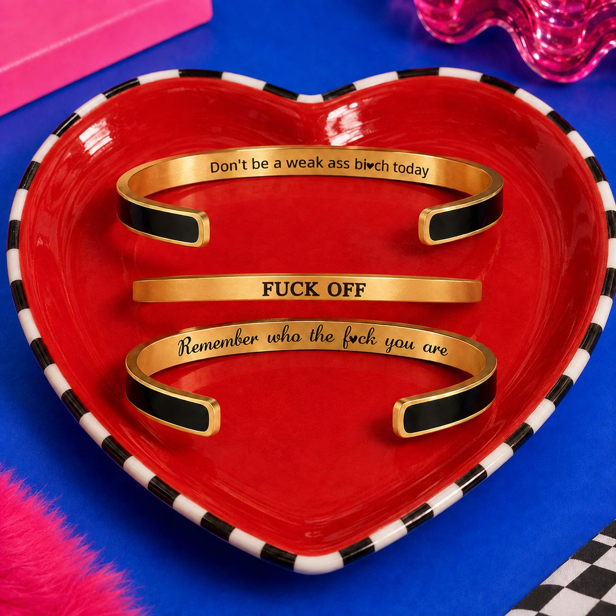 Two black and gold hidden message cuffs displayed with a slim gold Fuck Off bracelet