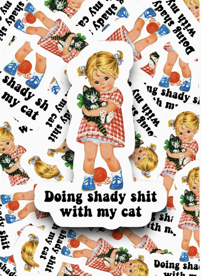 A die-cut sticker featuring a vintage-style illustration of a blonde girl in a red-and-white gingham dress holding a black-and-white cat, with the text 'Doing shady shit with my cat' on a white background. The sticker is shown layered over a repeating pattern of the same design.