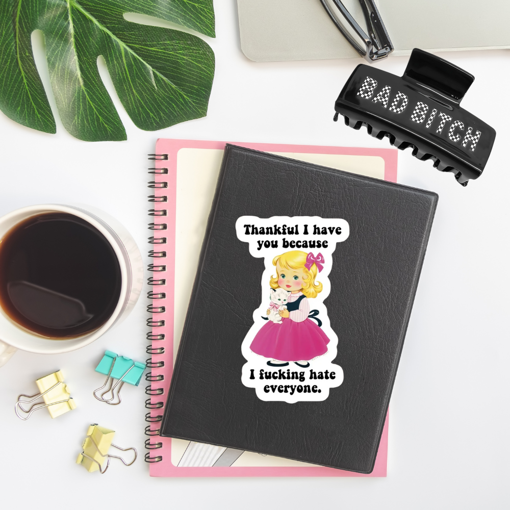Notebook with a sticker and a hairbrush on a desk with coffee and stationery.