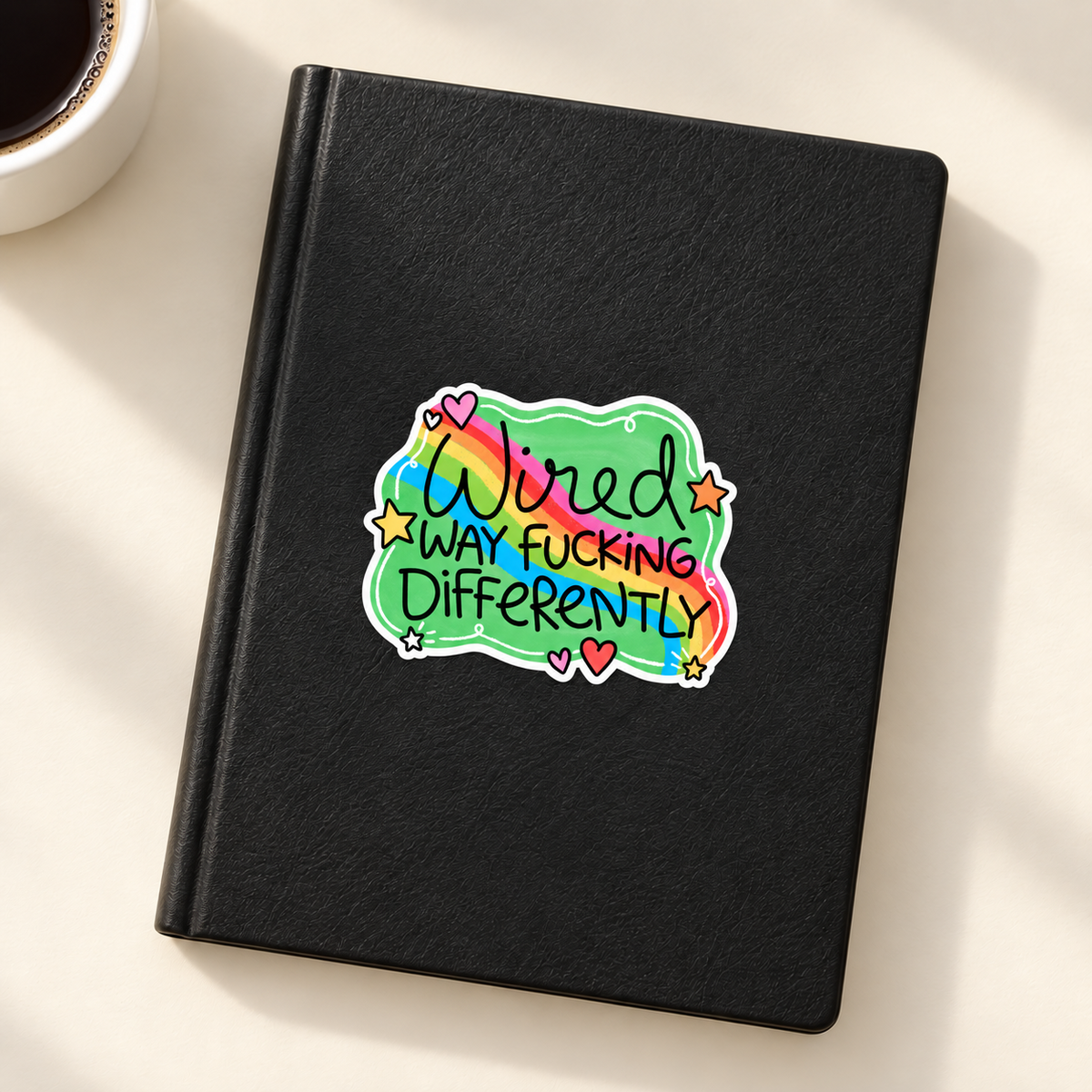 Wired Differently rainbow sticker on black notebook
